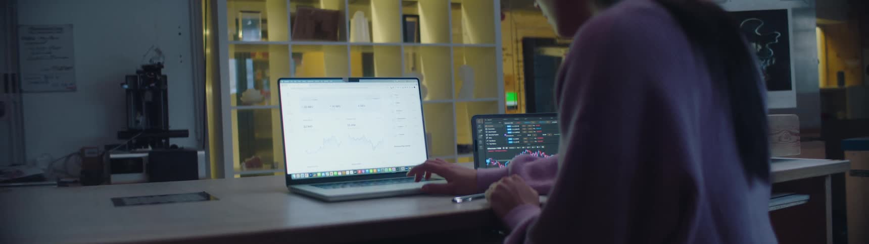 A woman is sitting at a desk and looking at a laptop