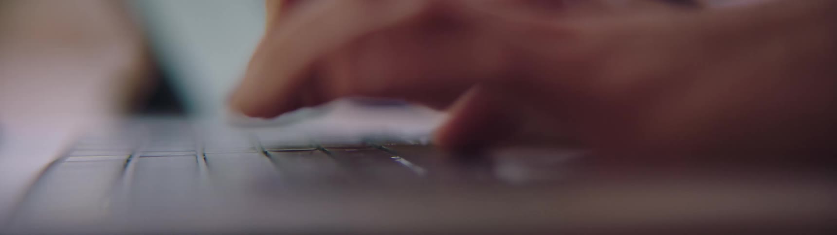 Close up of hands typing on the keyboard of a laptop over a desk