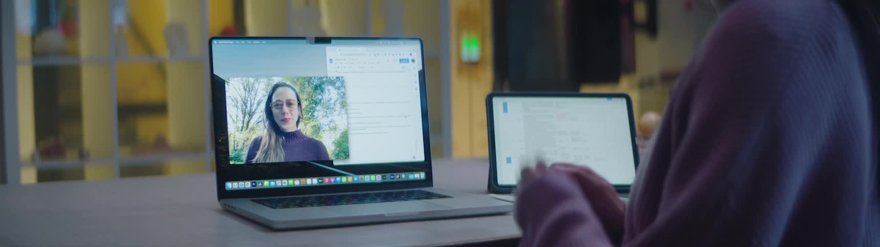 A woman waves at her friend during a video call on a laptop