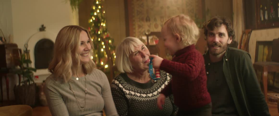 A grandmother and parents playing with a toddler boy at christmastime