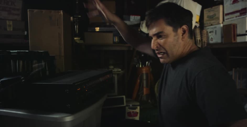 A man turns the knob on his stereo then throws it
