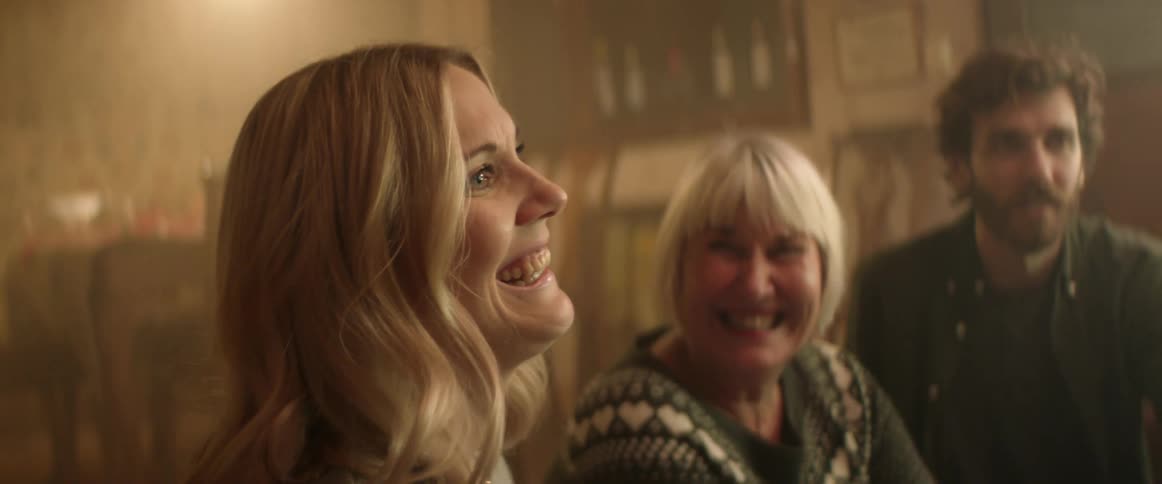 A child stands in front of his parents and grandmother in a home and they all laugh