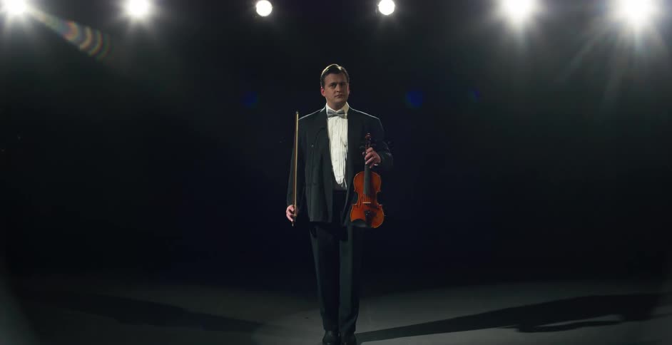 A man is standing on stage holding a string instrument