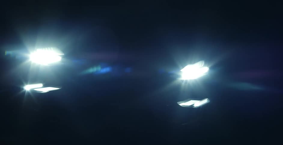 A vehicles headlights are glaring in the dark