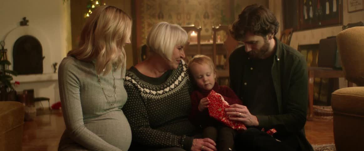 A family watch a boy open a christmas gift