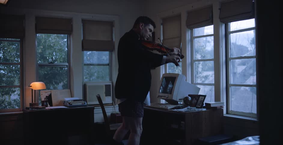 A man is playing a musical instrument inside of his house