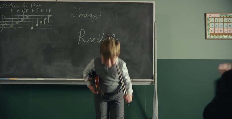 Parents applaud a young boy after a violin recital inside a classroom at school