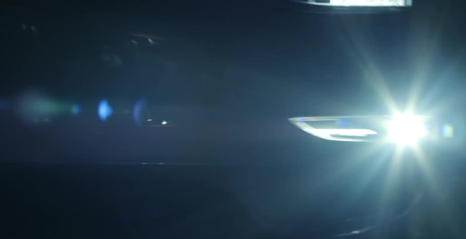 A car is shown at night with the headlights on