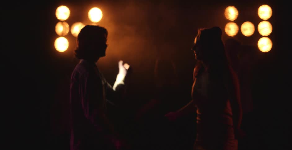A group of people are dancing in a club at night