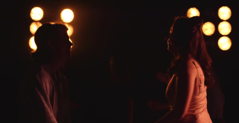 Young couple dancing on the dance floor of a night club under moving lights