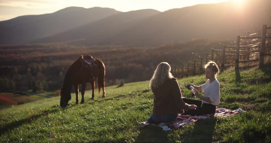 Two women pouring champagne at sunset