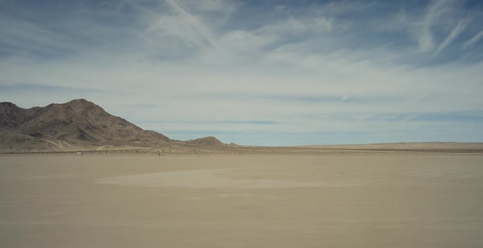 Mountains are across the desert under a cloudy sky