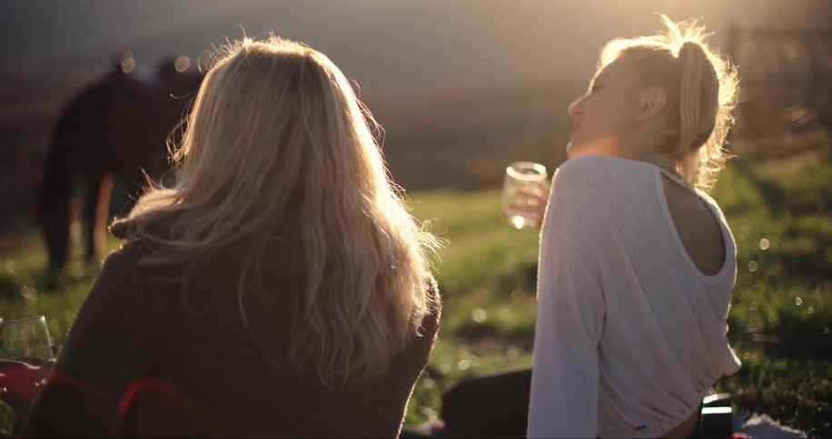 Two women sitting outdoors and drinking wine