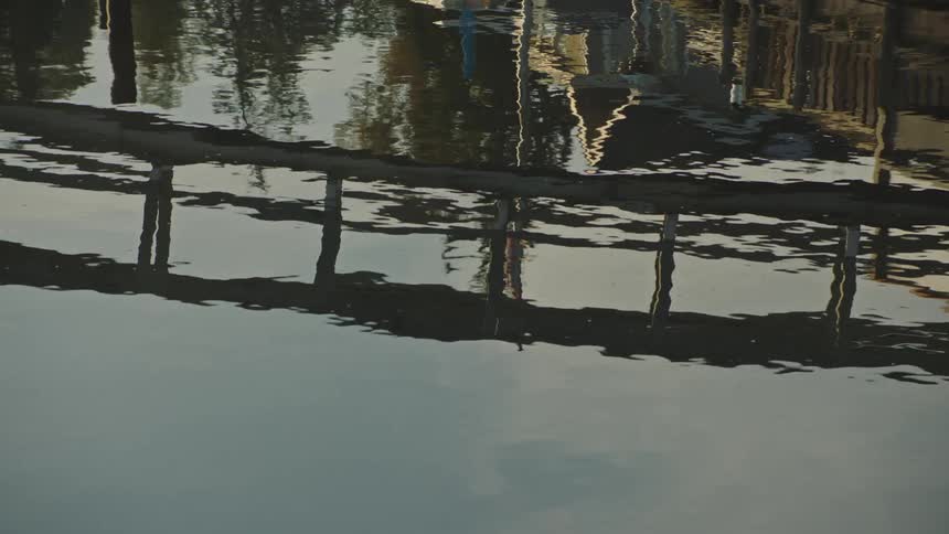 A marina pedestrian bridge is reflected in the water below