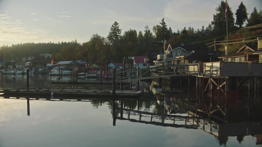 A marina dock at sunrise, reflecting in the calm water