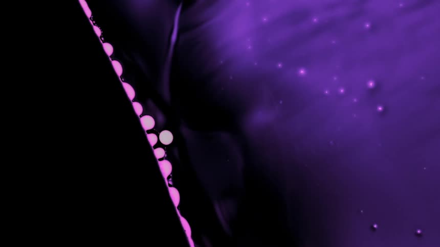 A microscopic image of purple fluids and dots moving and waving