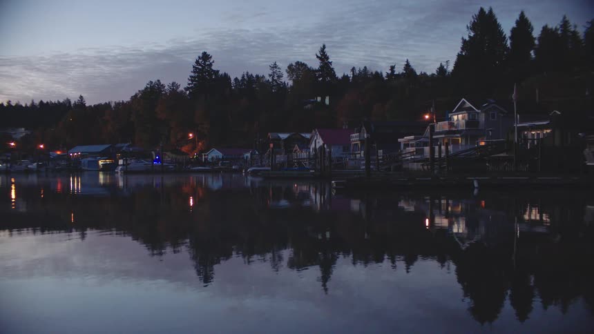 Houses reflected in the water by the shore in a fishing village at dusk