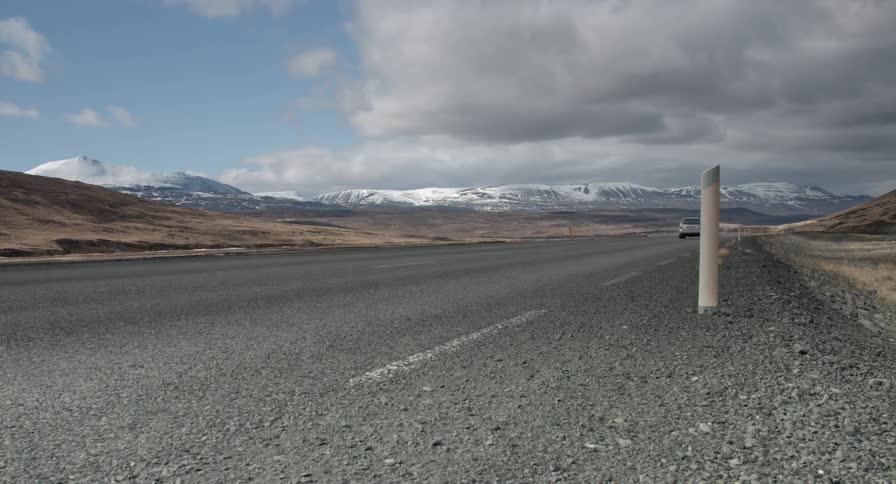 A car drives by on a long stretch of road