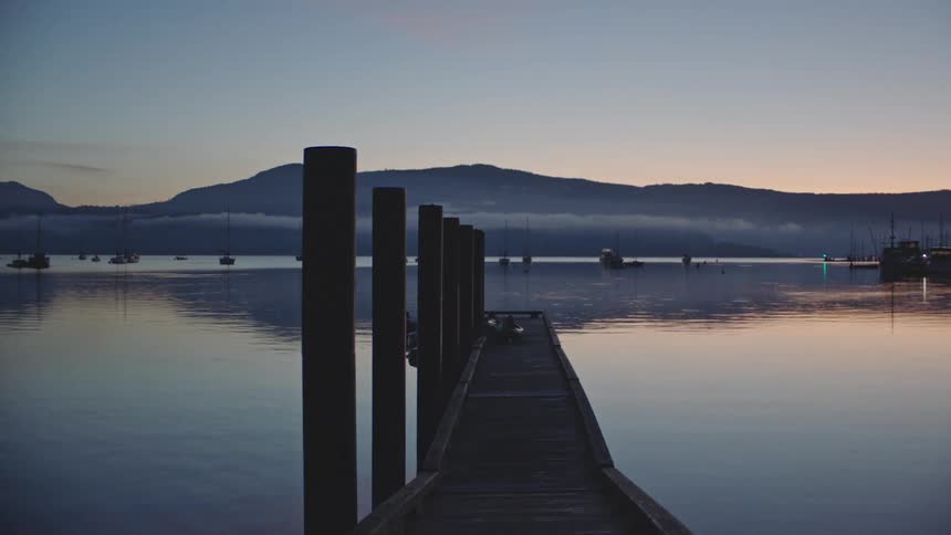 An ocean marina dock is shown in calm waters at dusk