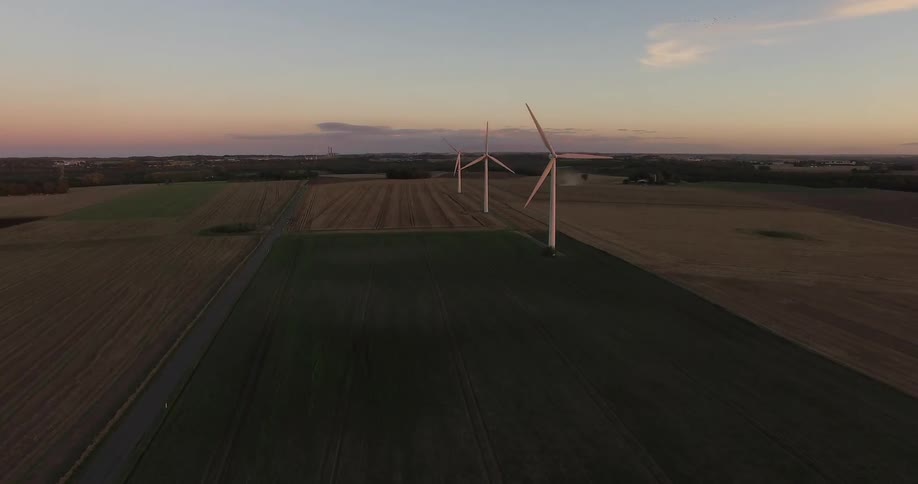 Windmills turn in a field near sunset