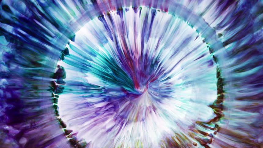 Circle of purple blue yellow and green liquid shrinks into the middle