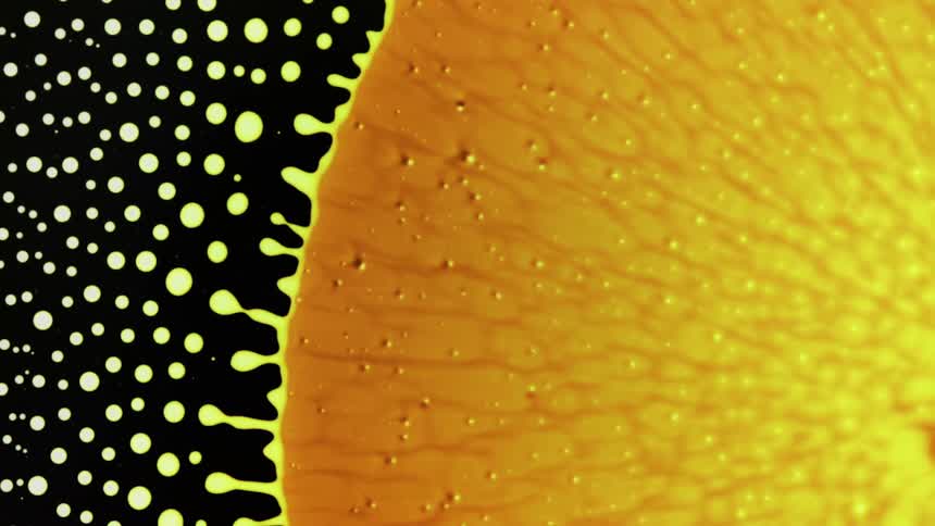 A bright orange yellow blob contracts and breaks off into small yellow dots