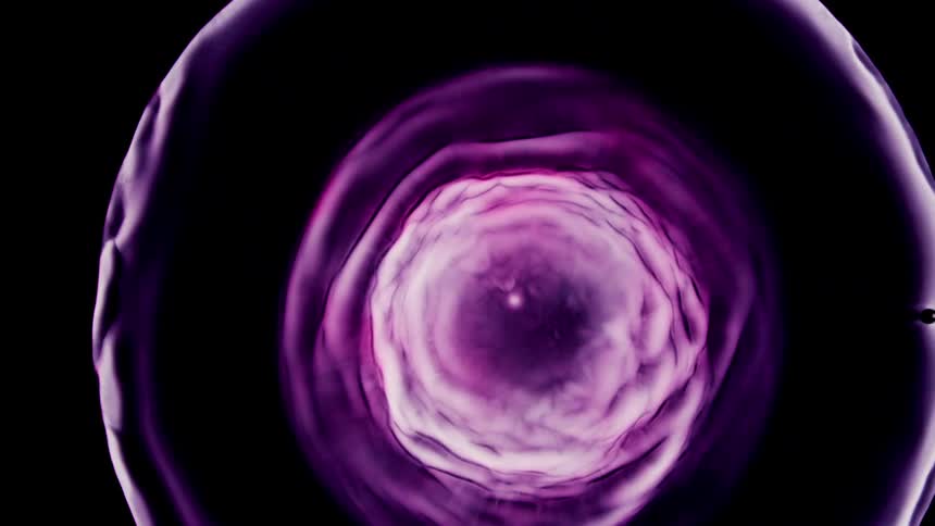 Bright lavender and pink colored rings spread out in a black background and circles ripple outward from the inside