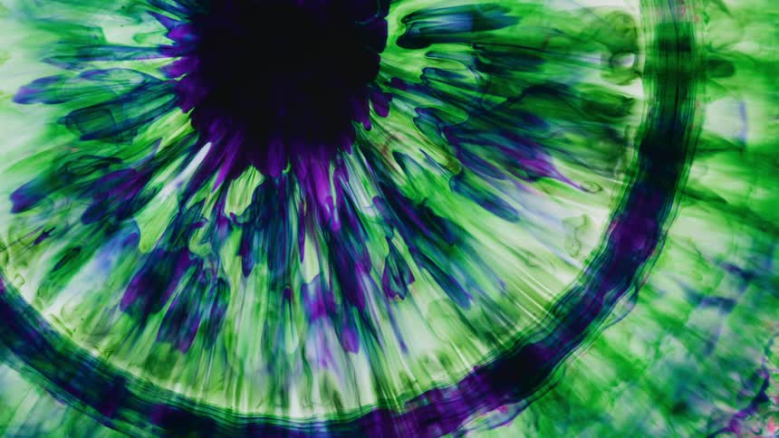 A burst of color slowly shrinks back to center in a kaleidoscope of green and purple