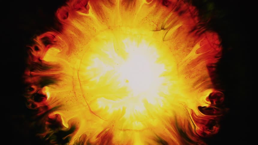 A yellow sphere burst from the darkness and explodes into red and orange flames of color