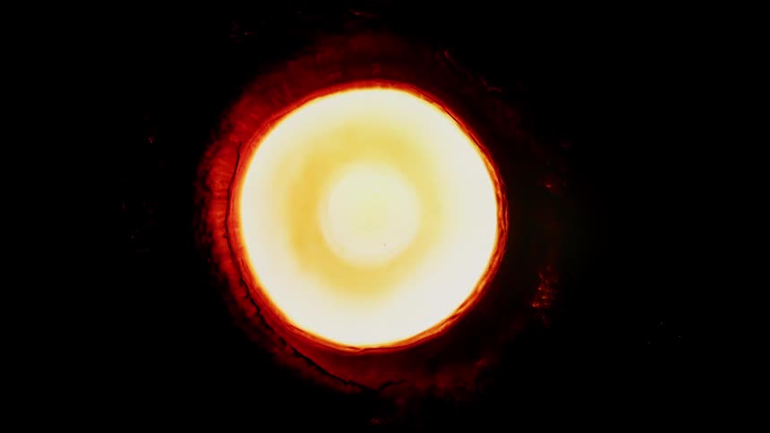 Yellow and white circles explode from a red cloudlike portal in the blackness