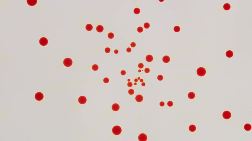 A circle of yellow orange contracts as it breaks off into small orange bubbles