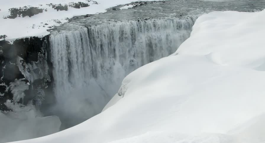 The Dettifoss waterfall in Iceland crashes to the bottom between snow covered mountains
