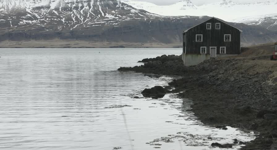A large house is by the shore near a mountain