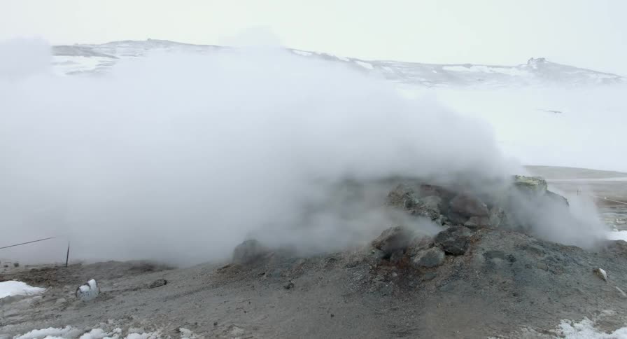 Smoke escapes a pile of rocks on a snowy day