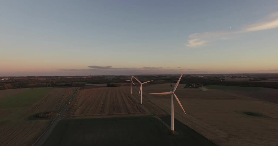 Windmills turn at sunset in a field