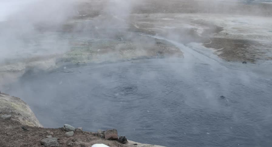 A small pond with geothermal activity in Iceland is steaming and bubbling below