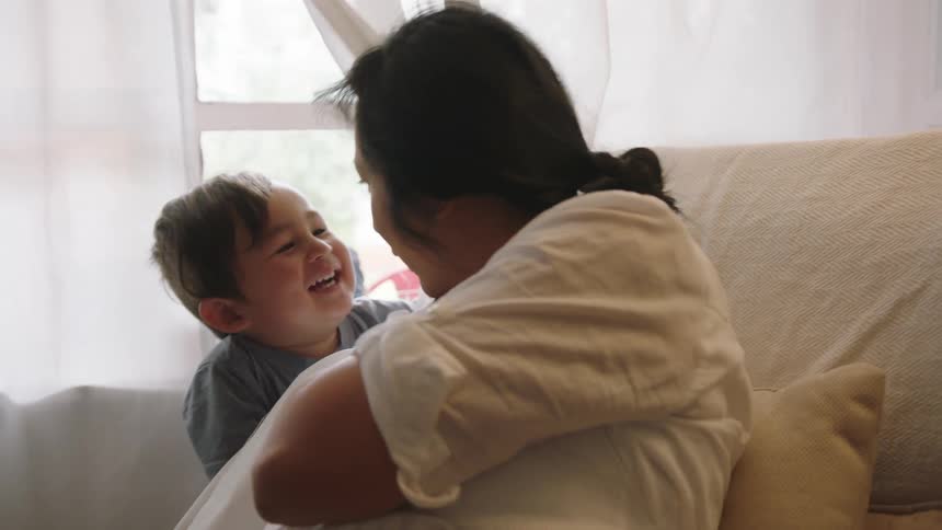 A pregnant mother plays with her son at home