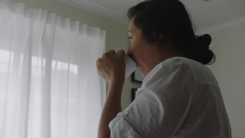 A woman drinks in her home