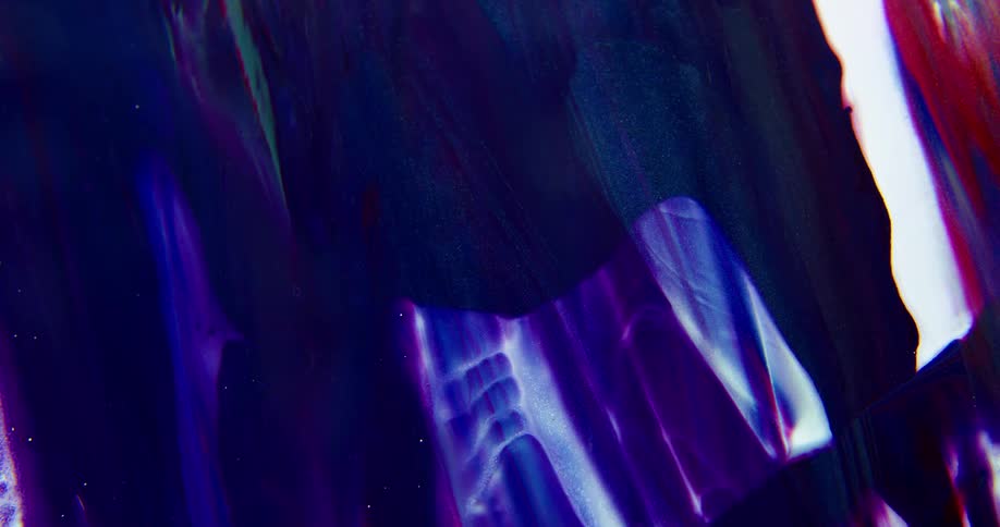 Thick blobs of liquid blue ink flowing down a backlit translucent surface