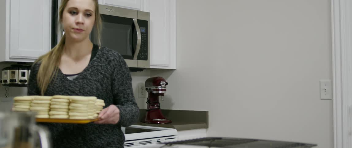 Woman moving a tray with many stacks of cookies before taking one