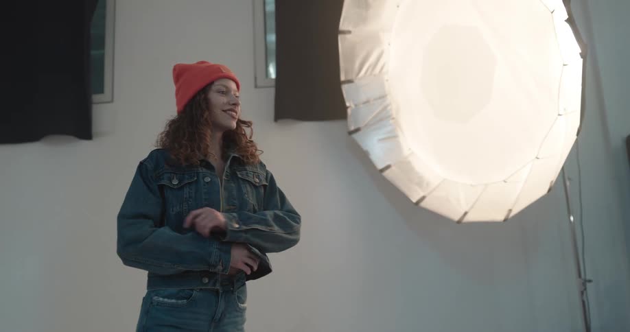 A woman is striking several poses in a photographers studio while lights flash from the camera
