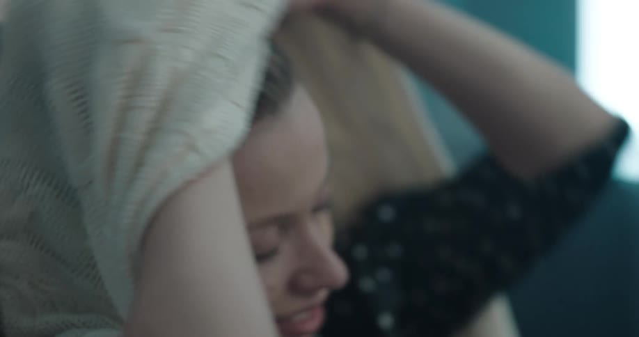A teenager changes out of her sweater in a locker room