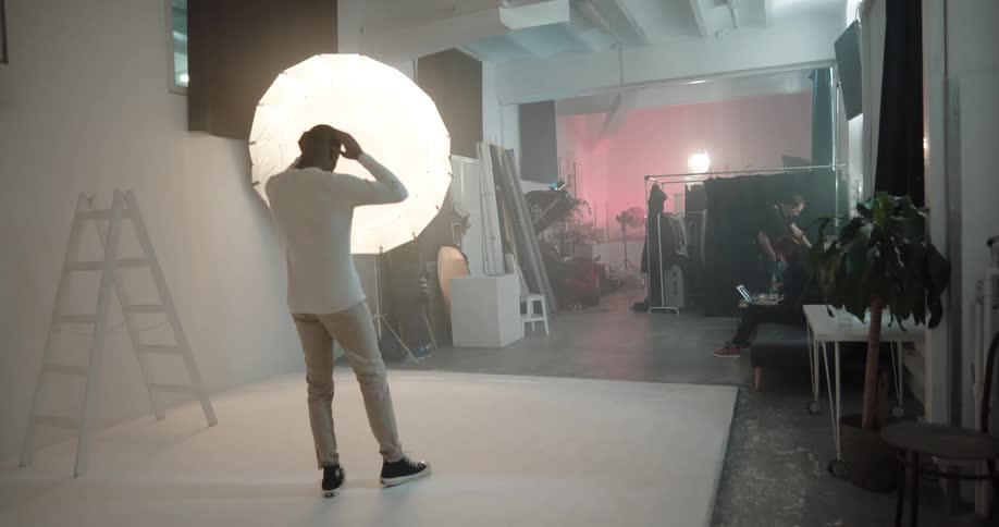 A photographer directs a model during a photo shoot in a studio