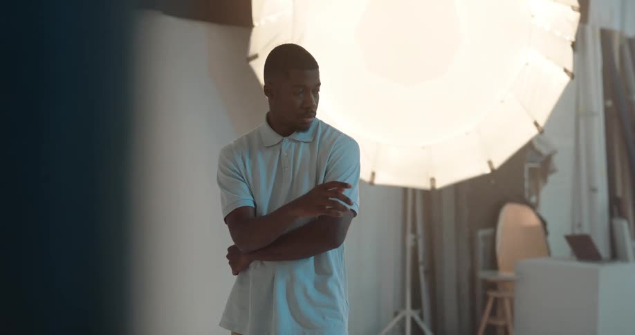 Young male model wearing a white shirt poses for the camera under flashing lights
