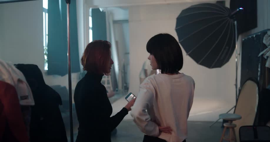 Two women looking at two models in a fashion photo shoot
