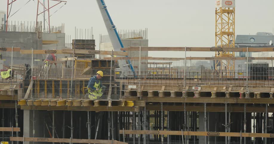 A construction worker in a hardhat using a hammer on a worksite