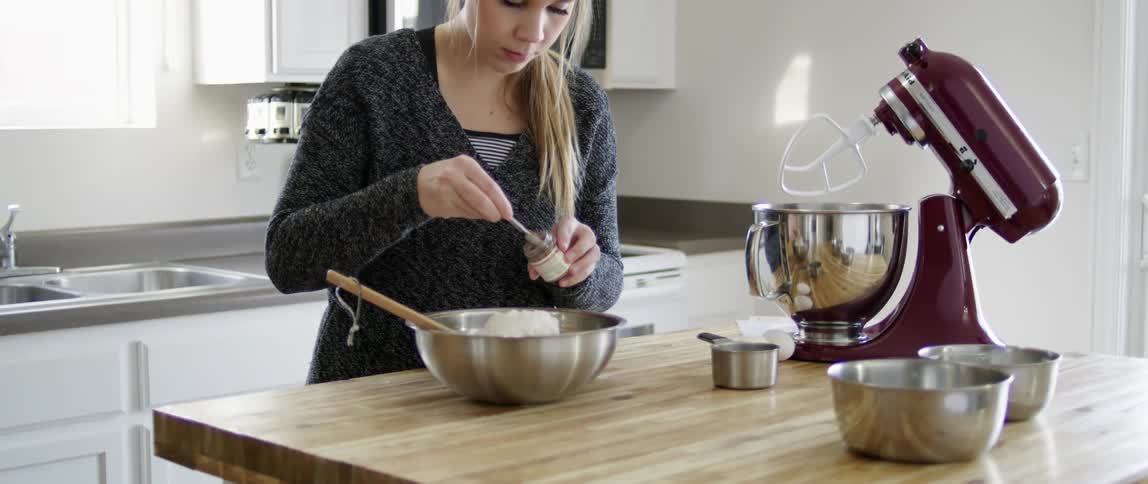 A woman is spooning something from a jar into a bowl
