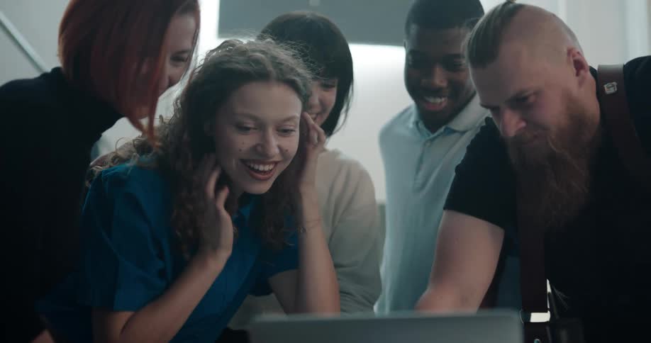 People gather around laptop smiling as they examine the contents