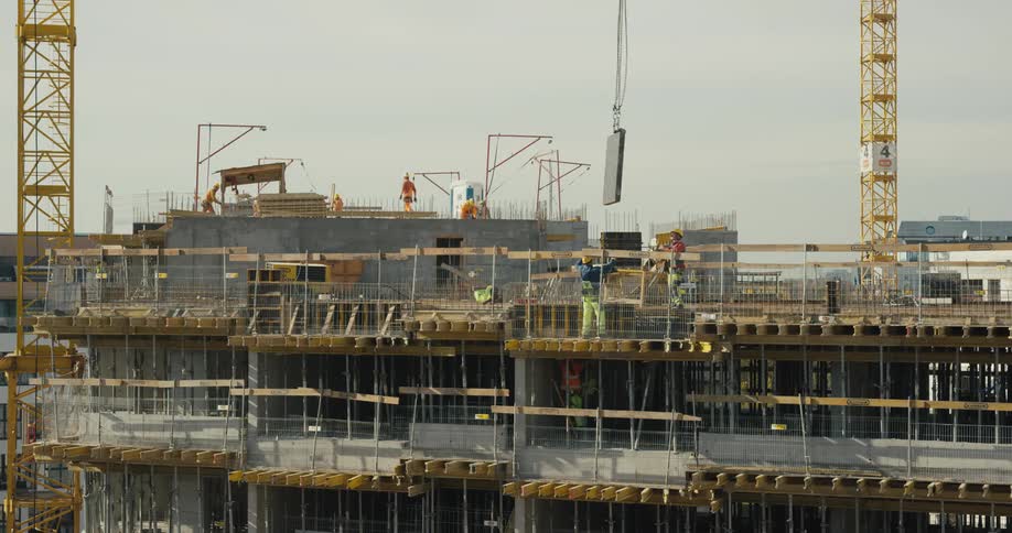 Group of workers wearing hardhats and protective equipment receive materials at a construction site