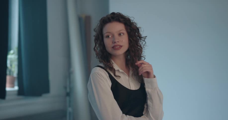 Young woman with curly hair poses for the camera on a photo shoot